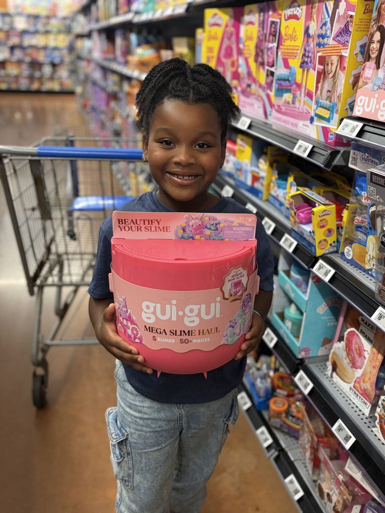 Moose Toys  Gui Gui Slime x Walmart Campaign. MomSelect Influencer's child holds Gui Gui Mega Slime Haul in Walmart aisle with smile. 